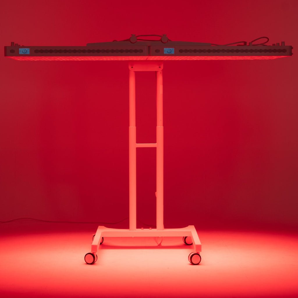 Heilys Dual Stand Horizontal to wysokie, prostokątne urządzenie na kółkach, które emituje żywe czerwone światło, oświetlając otoczenie. Jego solidna metalowa rama sugeruje, że jest przeznaczony do terapii światłem czerwonym lub podobnych zastosowań medycznych.