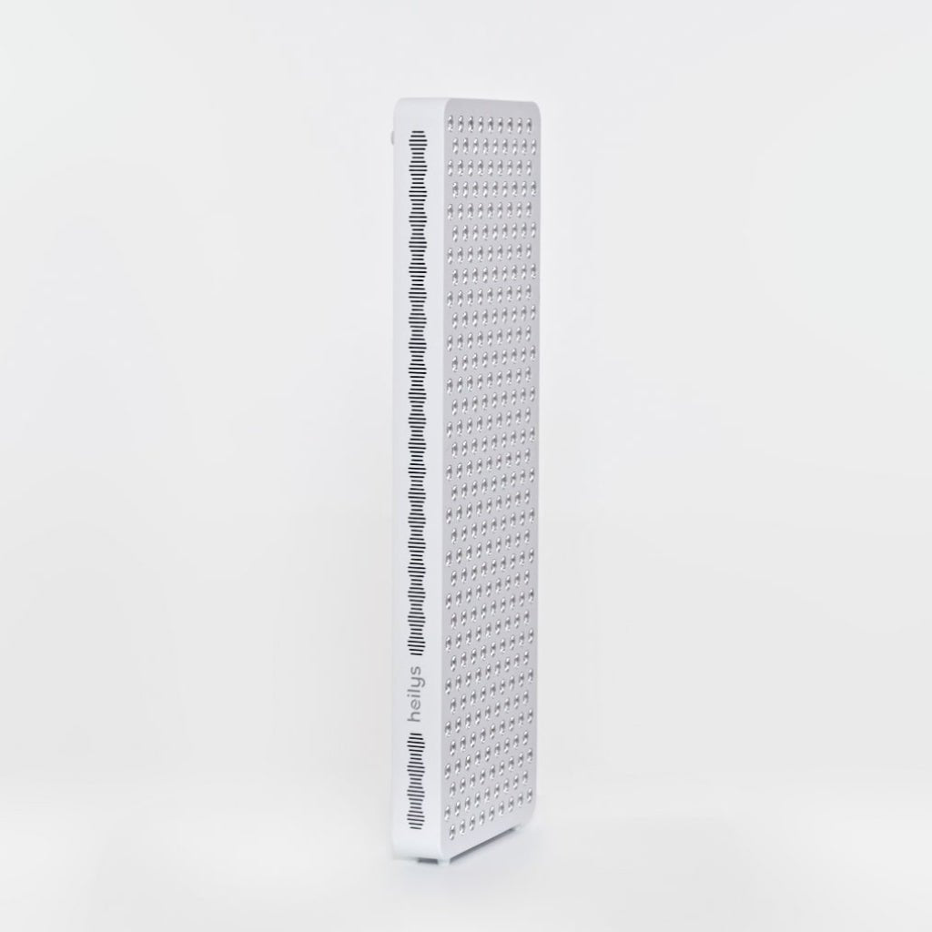 Wysoki, prostokątny biały panel LED z siatką małych okrągłych świateł z przodu i bocznymi szczelinami wentylacyjnymi, przeznaczony do terapii światłem, stoi pionowo na prostym białym tle.